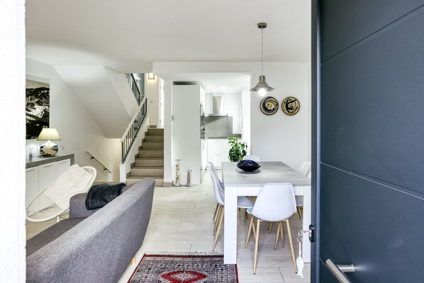 A modern interior with a staircase, dining area, and a sofa.