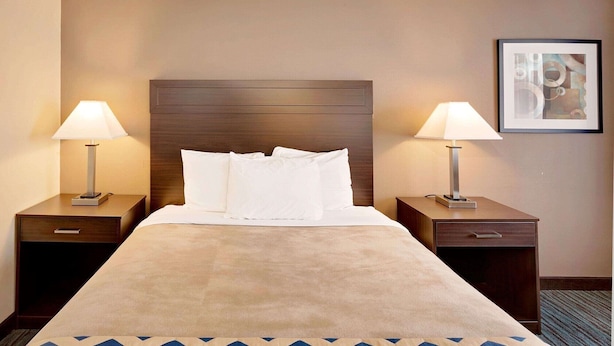 A hotel room with a large bed, two bedside tables with lamps, a framed picture on the wall, and a carpet with a geometric pattern. - Travelodge Aberdeen WA (Aberdeen)