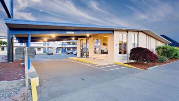 A motel with a covered parking area, a visible entrance, and a building with a flat roof.