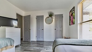A bedroom with a bed, a dresser, a TV, and a door with a mirror.