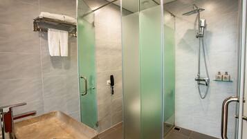 Een moderne badkamer met een douchecabine van glas, een marmeren wastafel en een handdoekrek.