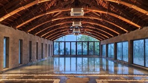 Une piscine intérieure spacieuse, dotée d’un haut plafond et de grandes fenêtres.