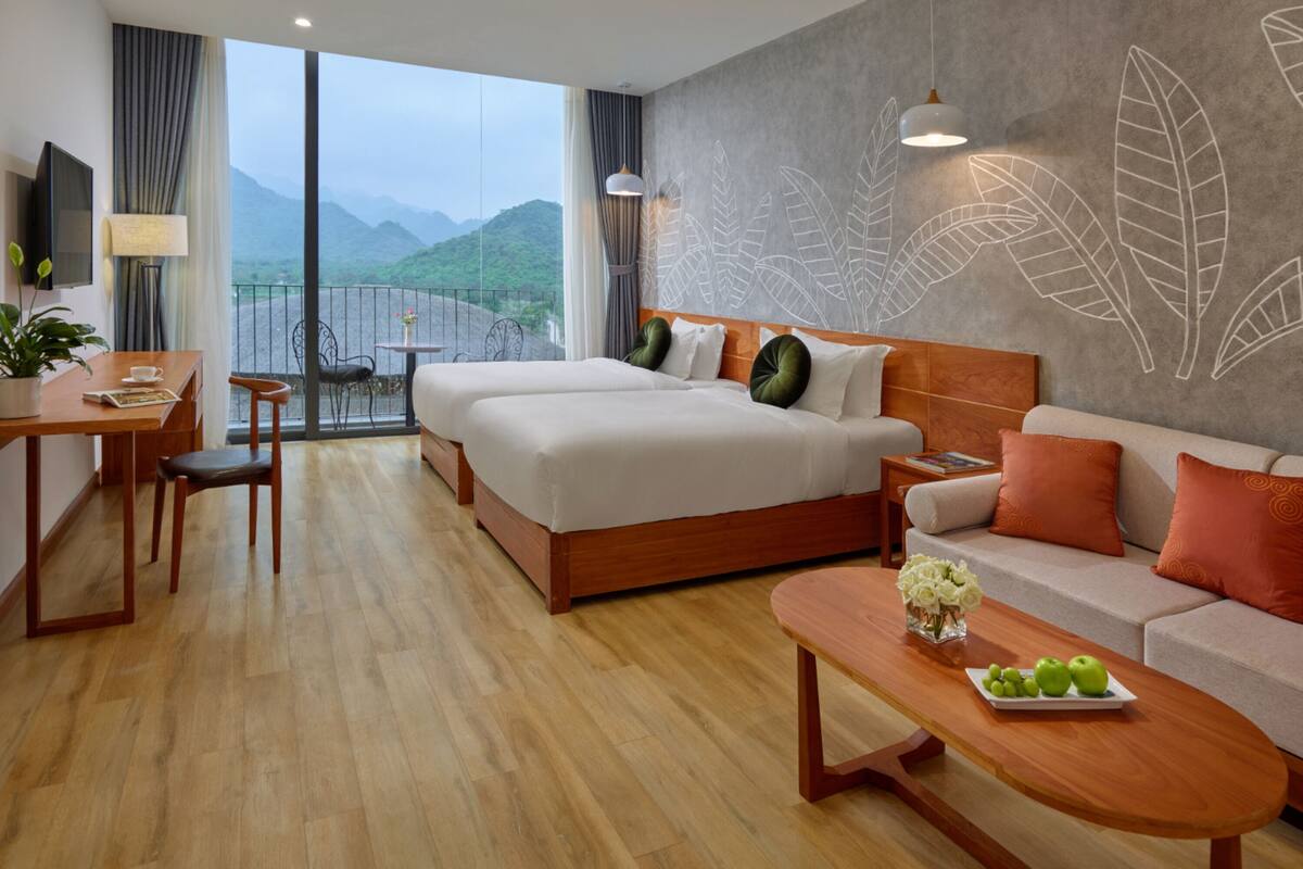 Quarto de hotel com varanda, uma cama, sofá, mesa de jantar e televisão.