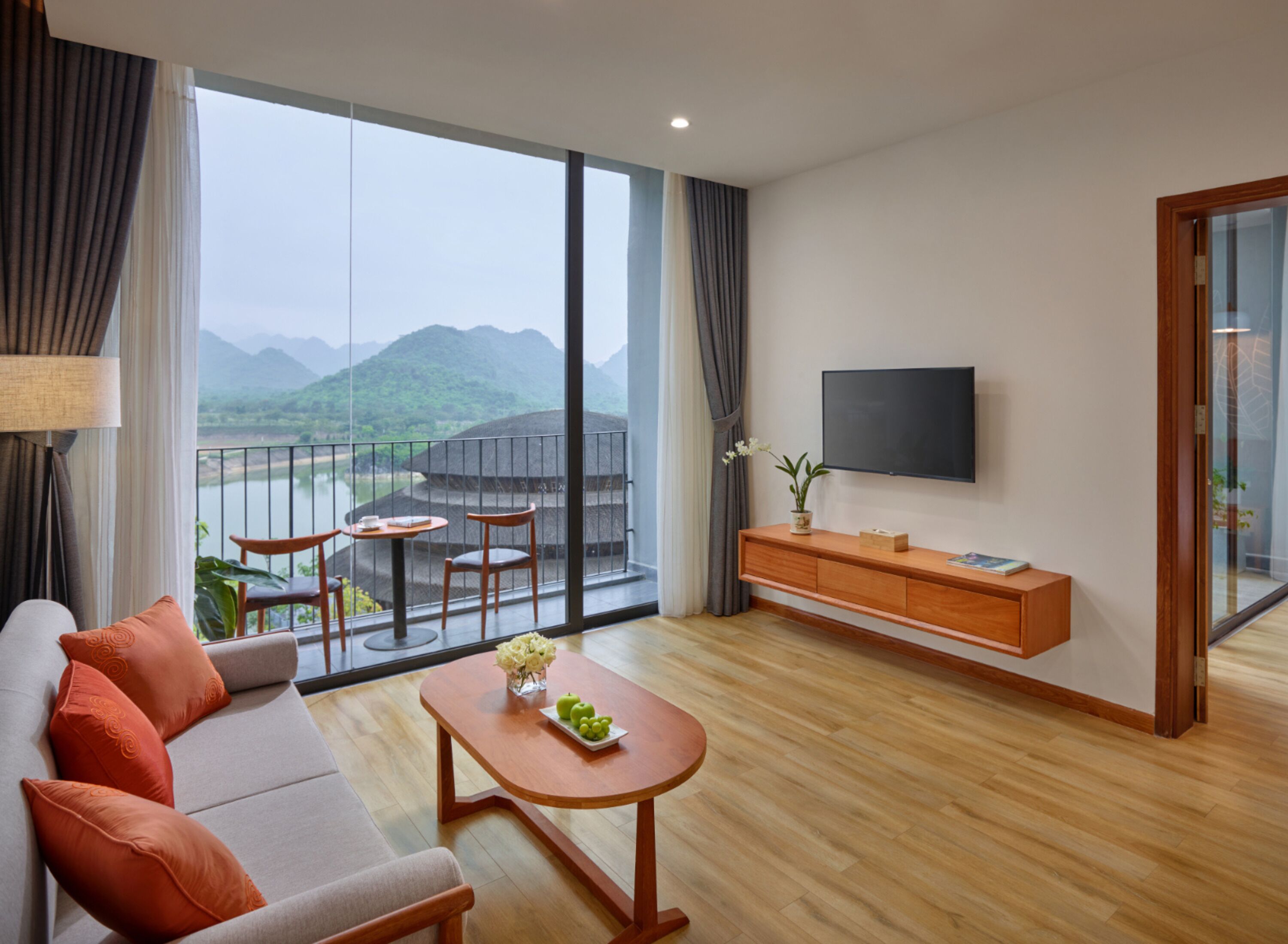 A modern living room with a sofa, coffee table, and a balcony with a view of mountains.