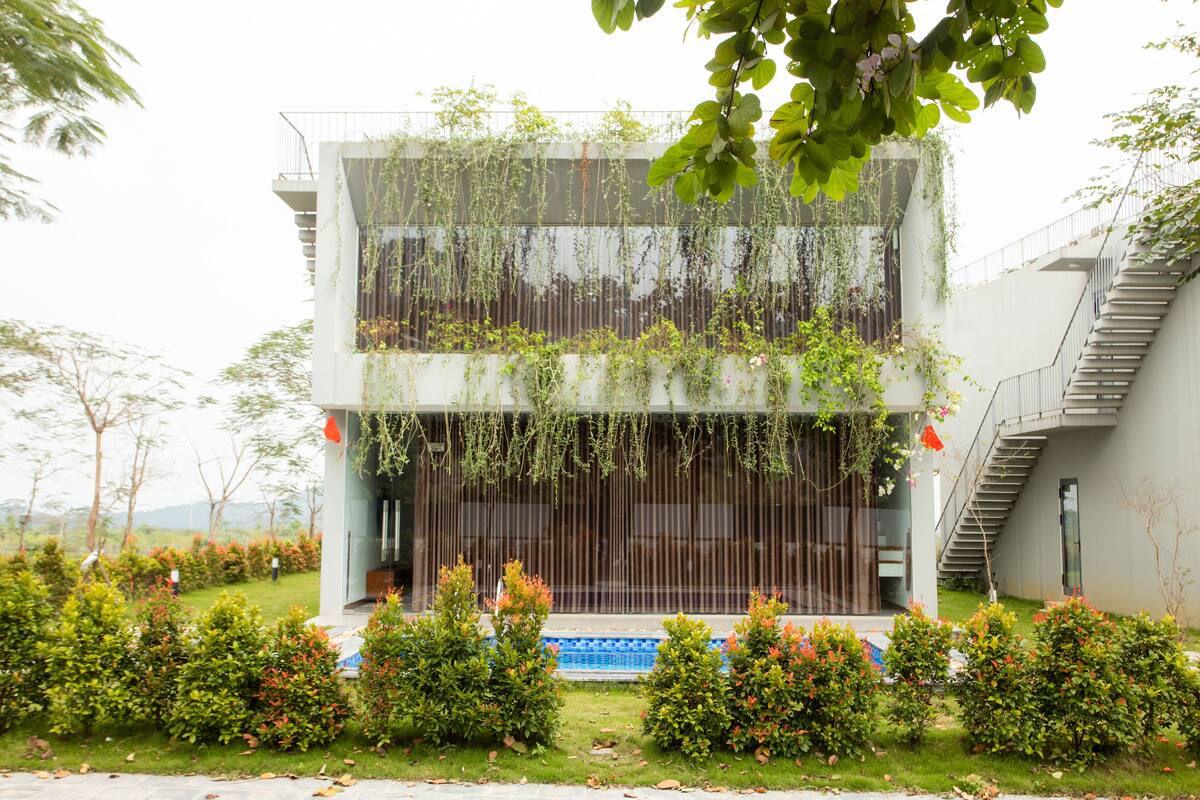 Um edifício moderno com fachada de vidro, uma escadaria à direita e uma pequena piscina na frente.