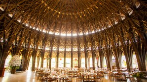 Un vaste espace intérieur doté d’un haut plafond en bambou aux motifs complexes, ainsi que de plusieurs tables et chaises.