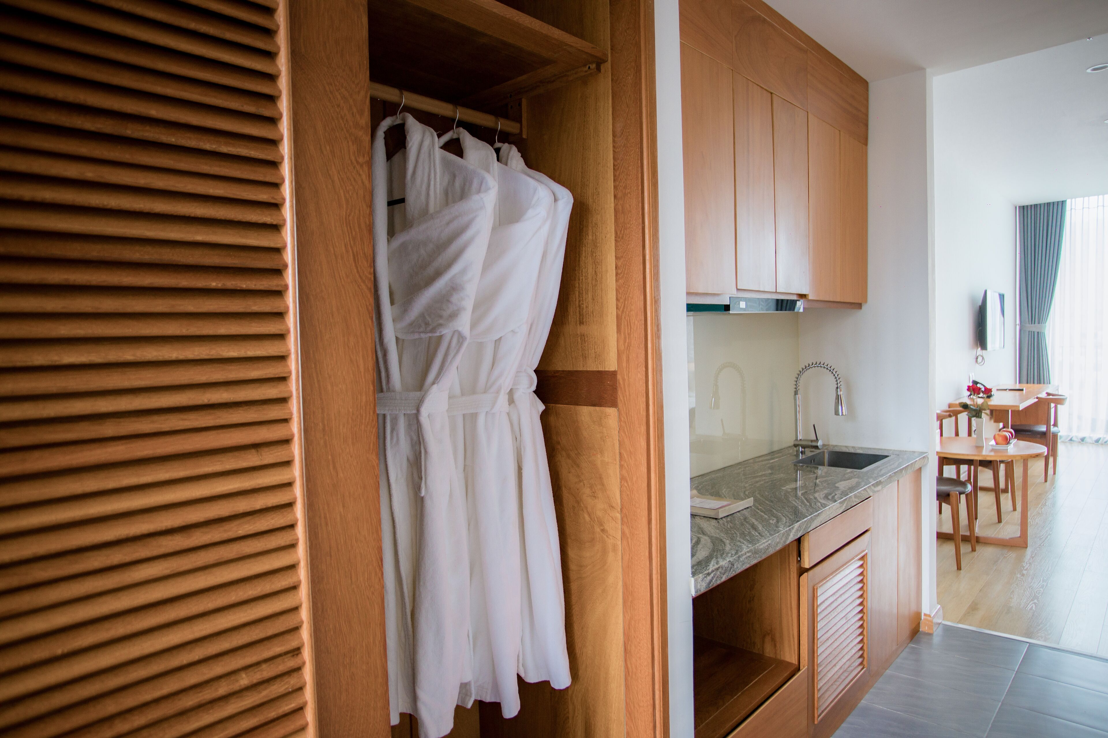 Una cocina moderna con armarios de madera, encimera de mármol y un comedor con mesa y sillas.