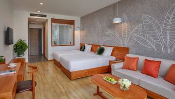 A modern hotel room with a large bed, a sofa, a coffee table, and a dining area.