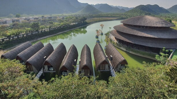 Un bâtiment de style traditionnel, doté d’un toit circulaire, entouré d’une rivière et de montagnes.