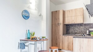 A modern kitchen with wooden cabinets, a marble countertop, and a small dining area with stools.