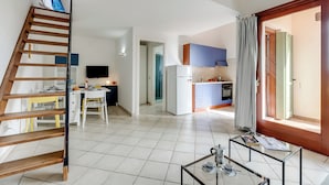 A modern apartment with a kitchen, dining area, and a staircase.