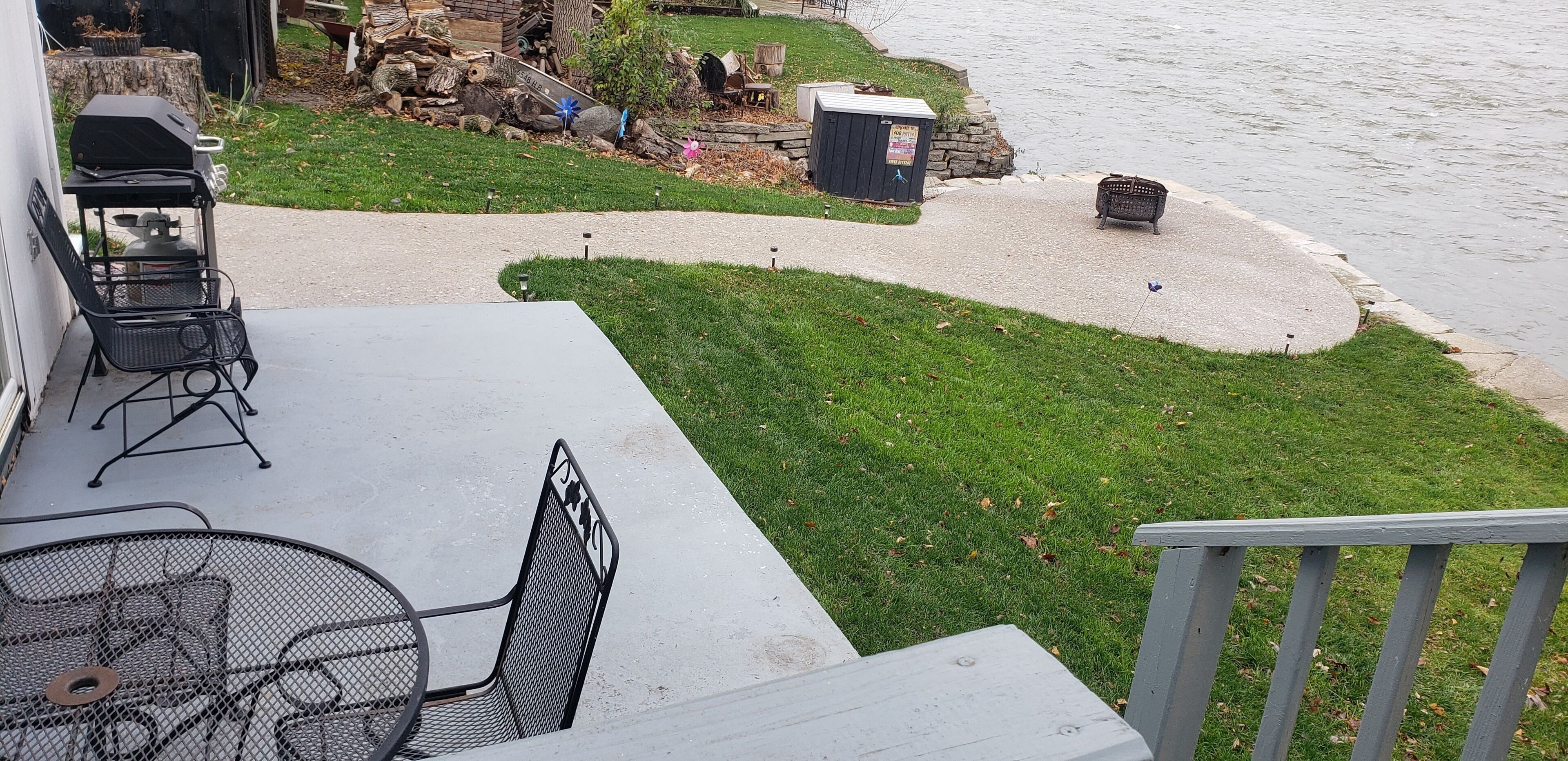 A patio with a grill, outdoor seating, and a view of a river.