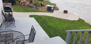 A patio with a grill, outdoor seating, and a view of a river. - Fox River Retreat #1 (Menasha)