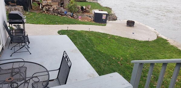 A patio with a grill, outdoor seating, and a view of a river.