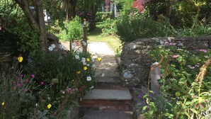 Un sentier de jardin menant à un mur de pierre surmonté d’un escalier.