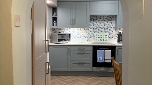 Uma cozinha com armários azul claro, um micro-ondas e um piso com padrão losango.