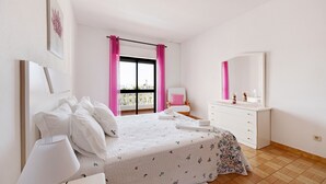 A bedroom with a bed, bedside table, dresser, and a window with curtains. - Apartment 'Casa Atlântico nº2' close to the Sea with Shared Pool & Wi-Fi (Lagos)