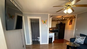 A living room with a dark blue sofa, a ceiling fan, and a kitchen in the background. - Ocean view 2 bedrooms  with a shared pool. 5 (Hampton)