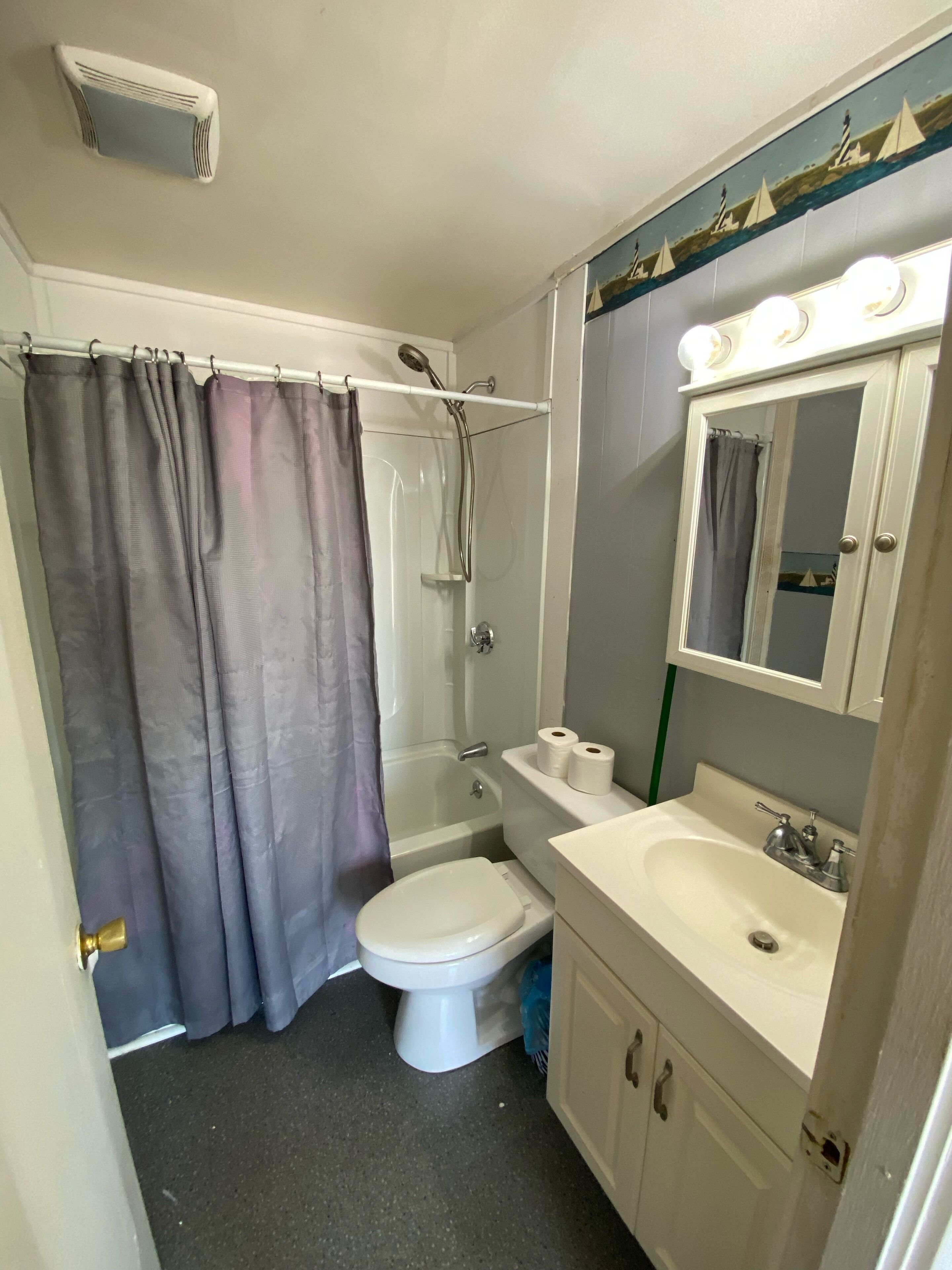 A bathroom with a bathtub, toilet, sink, and a mirror above the sink.