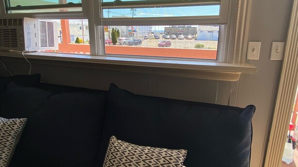 A room with a window overlooking a parking area, a radiator, and a dark-colored sofa with patterned cushions. - Ocean view 2 bedrooms  with a shared pool. 5 (Hampton)