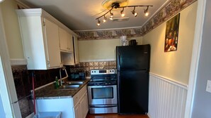 A compact kitchen with white cabinets, a black refrigerator, stainless steel appliances, and a patterned backsplash. - Ocean view 2 bedrooms  with a shared pool. 5 (Hampton)