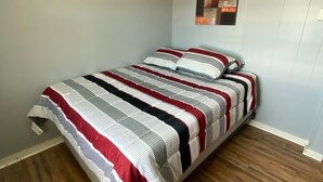 A bedroom with a bed, wooden flooring, and a wall with a lighthouse mural. - Ocean view 2 bedrooms  with a shared pool. 5 (Hampton)