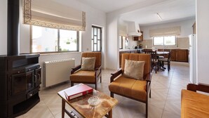 A living room with a fireplace, leather chairs, a dining table, and a kitchen in the background. - Apartment 'Casa Atlântico nº3' close to the Sea with Shared Pool & Wi-Fi (Lagos)