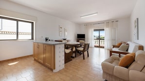 Een ruime woonkamer met een eettafel, bank en een keukeneiland.