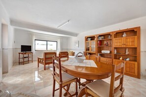 Un coin repas avec une table et des chaises en bois, un téléviseur et une bibliothèque.