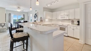 Una cocina moderna con armarios blancos, una isla grande e iluminación colgante.