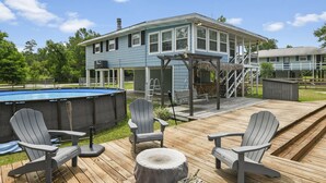Een huis met een terras, een zwembad en Adirondack stoelen.