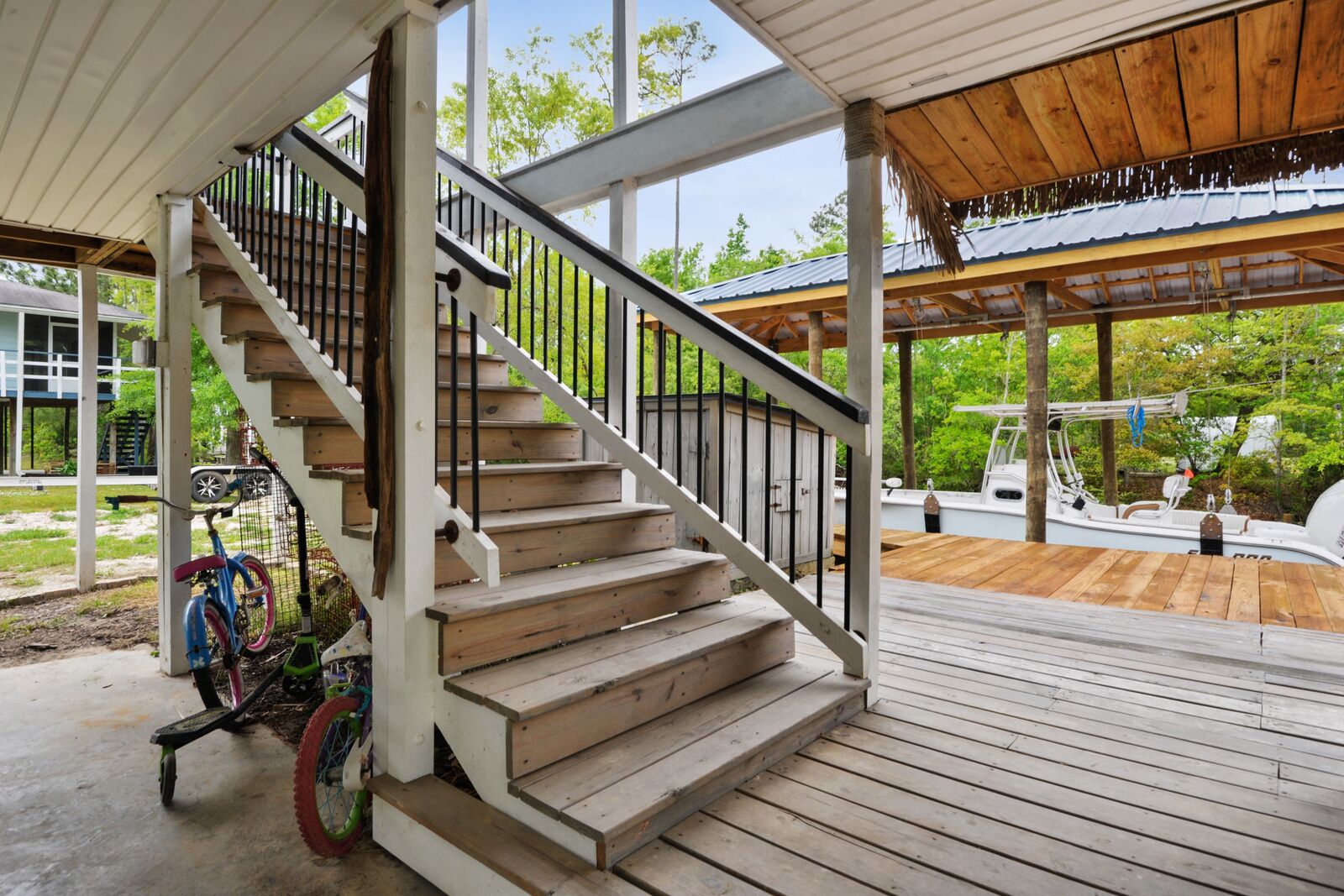 A wooden deck with a staircase leading to a covered area.
