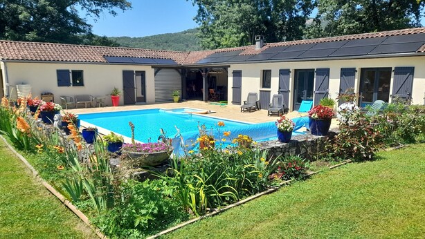 Une maison à deux étages avec une piscine, un espace salon extérieur et des plantes en pot.