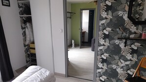 Une chambre à coucher comprenant un lit, une armoire, une chaise et une porte donnant sur une autre pièce.