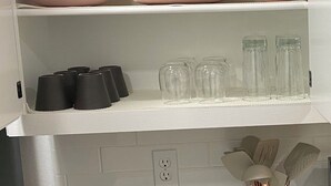 A kitchen with white cabinets, a marble countertop, and a power outlet.