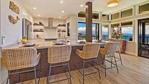 A modern kitchen with a central island, bar stools, and a view of the ocean.