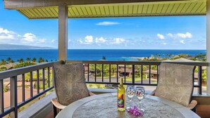 A balcony with a table, chairs, and a bottle of alcohol.