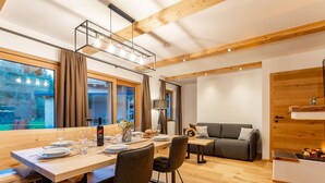A modern dining area with a wooden table set for four, a sofa, and a fireplace. - Very luxurious apartment with sauna (Mauterndorf)