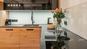A modern kitchen with a central island, a built-in oven, and a large mirror above the countertop. - Very luxurious apartment with sauna (Mauterndorf)