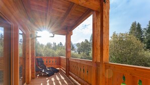 A wooden deck with two lounge chairs facing a scenic view of trees and mountains. - Very luxurious apartment with sauna (Mauterndorf)