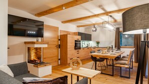 Una sala de estar moderna con chimenea, muebles de madera y un comedor con mesa y sillas.