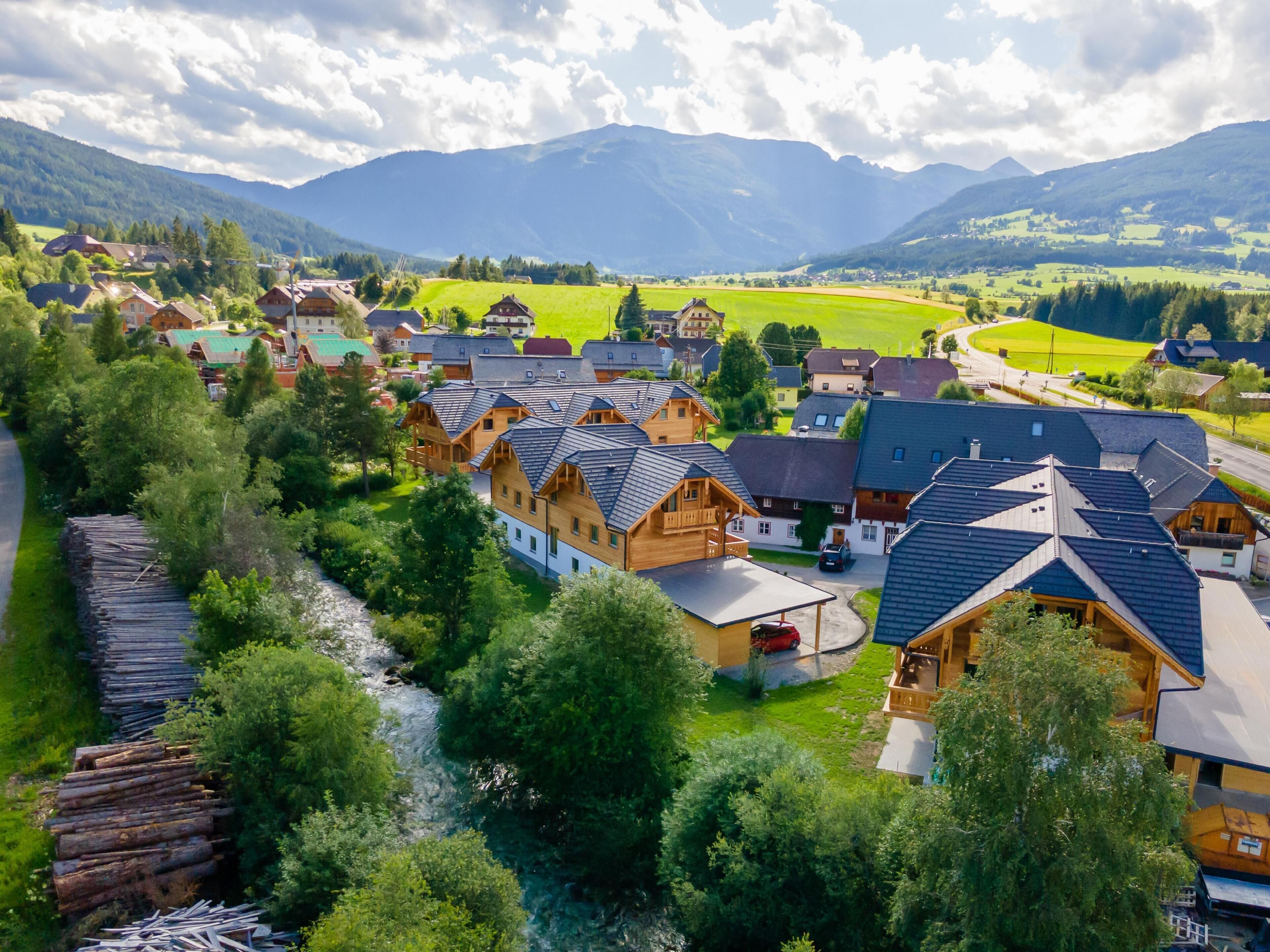 Un village avec des maisons traditionnelles en bois, une rivière et des montagnes en arrière-plan.