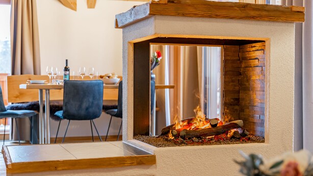 Un intérieur moderne agrémenté d’une cheminée en pierre, de meubles en bois et d’un coin repas.