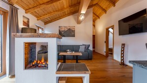Un salon chaleureux avec une cheminée, un plafond en bois et un téléviseur à écran plat.