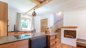 A modern kitchen with a built-in island, wooden flooring, and a fireplace. - Exclusive apartment with private sauna (Mauterndorf)