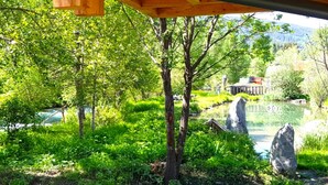 A lush garden with a wooden pergola, a pond with rocks, and a building in the background. - Exclusive apartment with private sauna (Mauterndorf)
