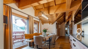 Zona pranzo in legno con tavolo imbandito per quattro persone, una panca e vista su una terrazza esterna.