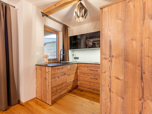Una cocina compacta con armarios de madera, un grifo negro y una ventana con cortinas.