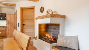 Ein gemütliches Zimmer mit Kamin, Holzmöbeln und einer Tür zu einem weiteren Bereich.