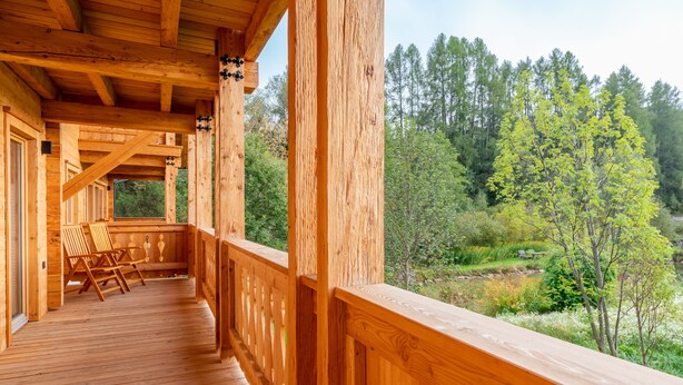 Eine Holzterrasse mit Stühlen und Blick auf ein bewaldetes Gebiet.